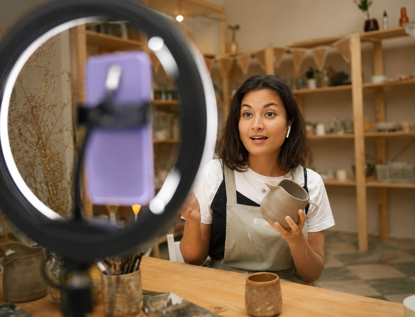 Lojista gravando vídeo de uma peça de roupa pelo celular para vender no TikTok Shop