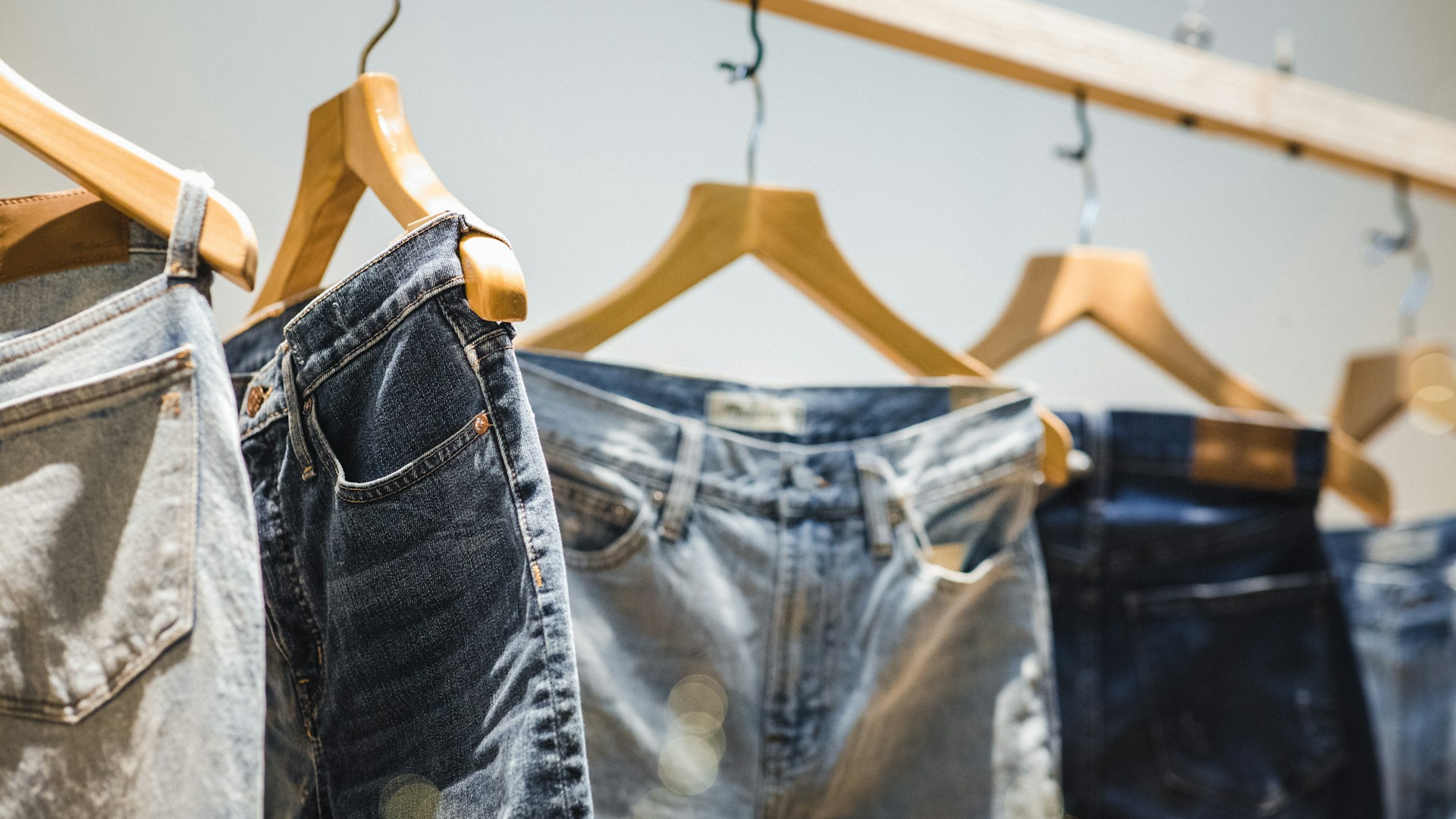 calças jeans penduradas em cabides de madeira - tendências jeans 2027