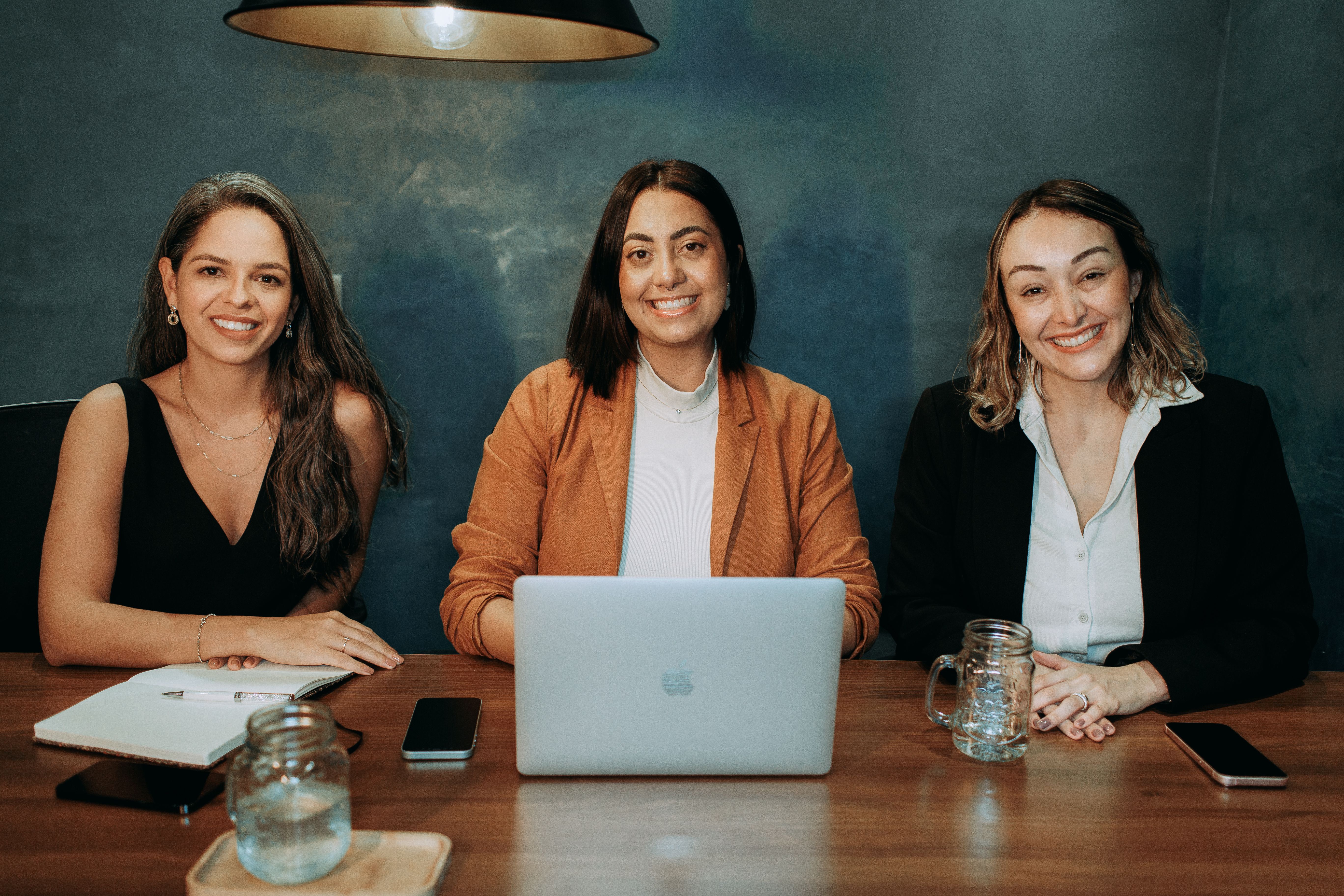 Empreendedora de óculos usando o celular e o notebook na sua loja, gestão financeira para pequenas empresas